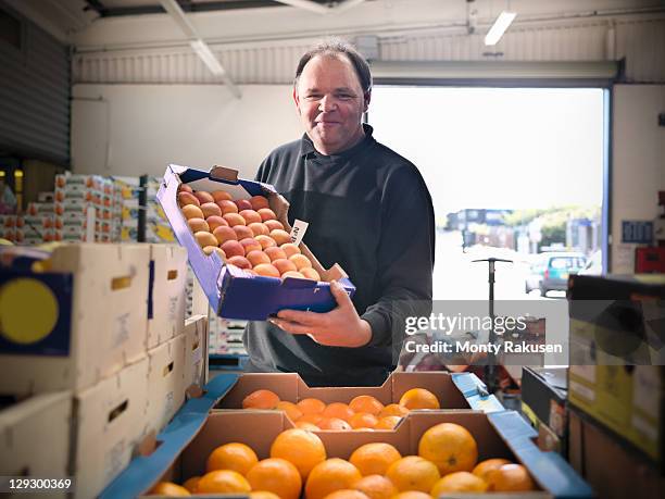 greengrocer with apricots and oranges - mature adult foto e immagini stock