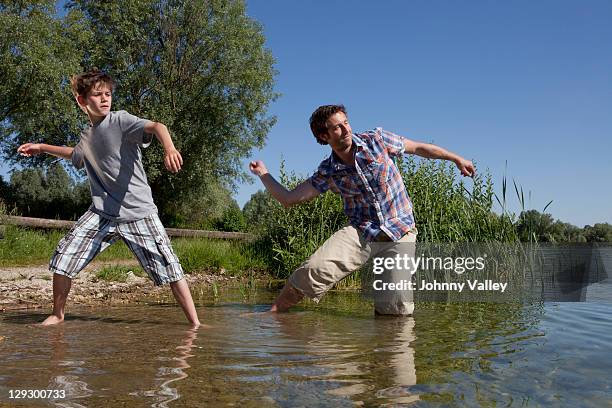 father and son skipping rocks on lake  - skip stockfoto's en -beelden