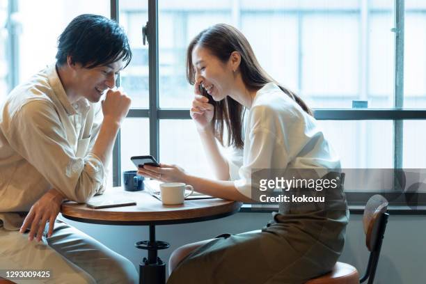 una coppia che fa una conversazione divertente con il sorriso in un bar - happy smile with phone foto e immagini stock