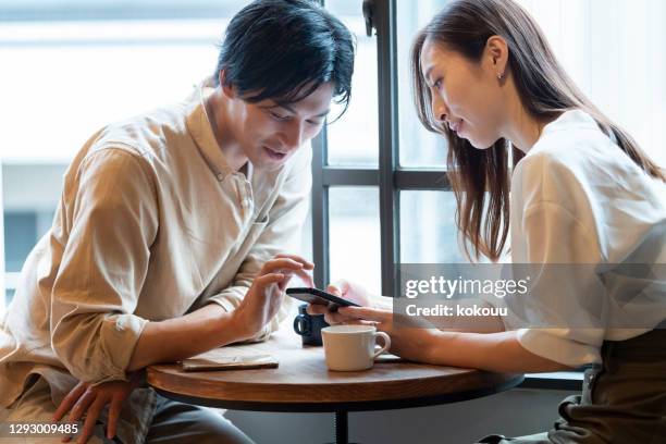 カフェで楽しい会話をしているカップル - スマホ レストラン ストックフォトと画像
