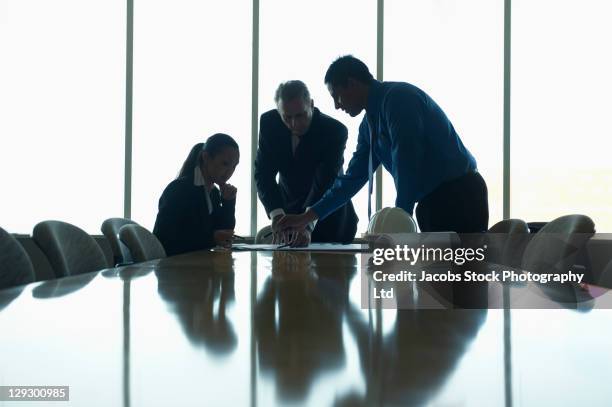 business people looking at blueprints in conference room - group of businesspeople standing low angle view stock pictures, royalty-free photos & images