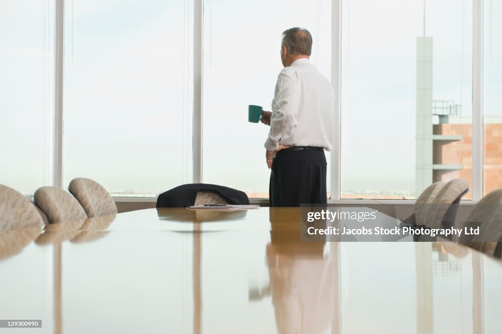 Hispanic businessman drinking coffee in conference room