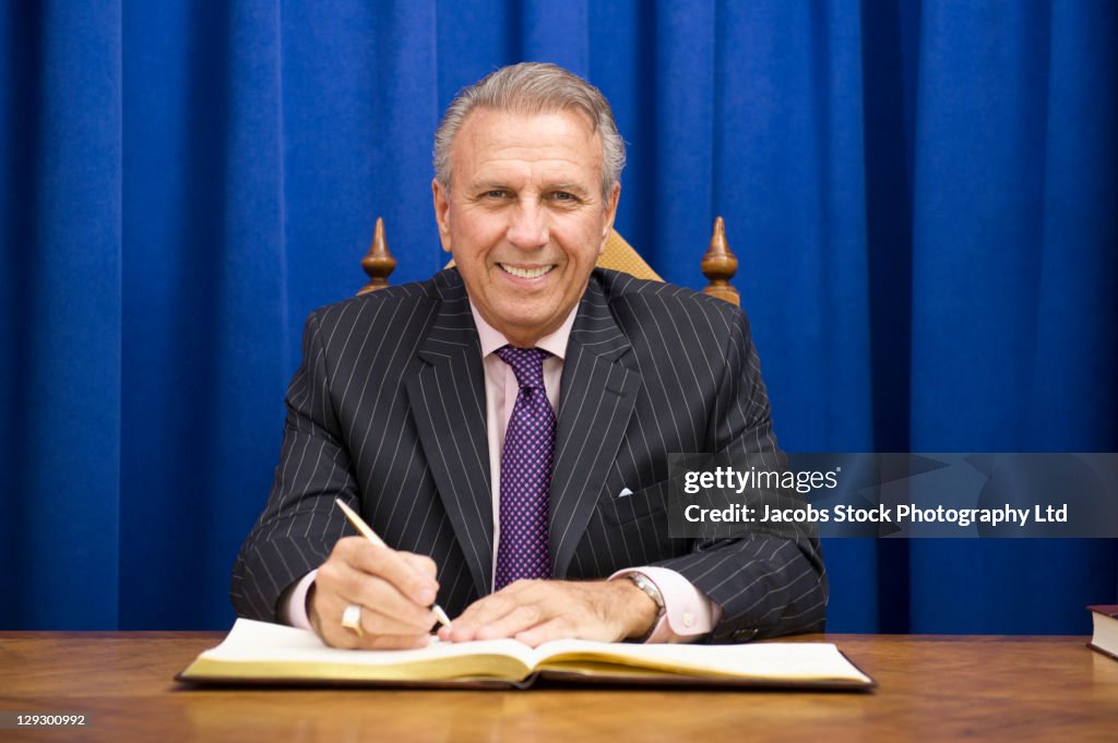 Hispanic politician signing book at desk