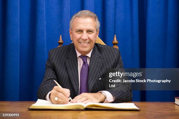 hispanic politician signing book at desk - mayor imagens e fotografias de stock