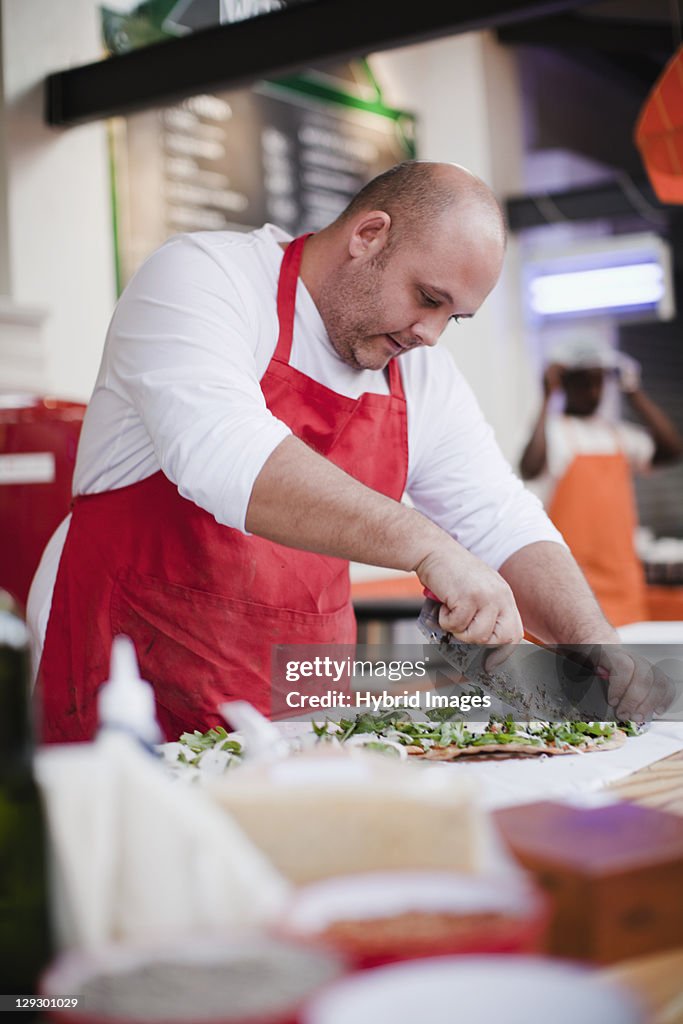 Chef slicing pizza in kitchen