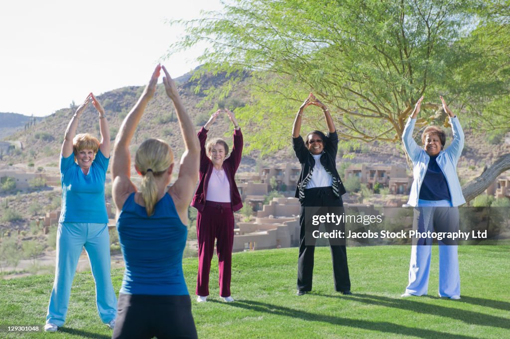 Women taking exercise class outdoors