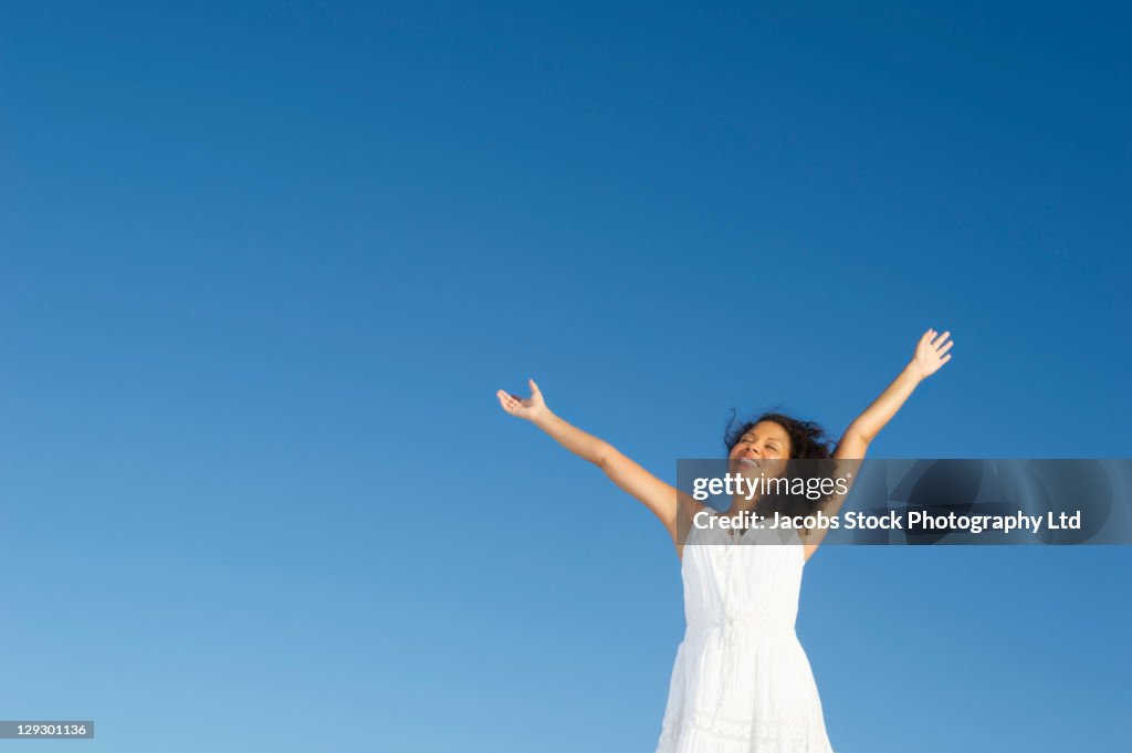 Mixed race woman standing outdoors with arms raised