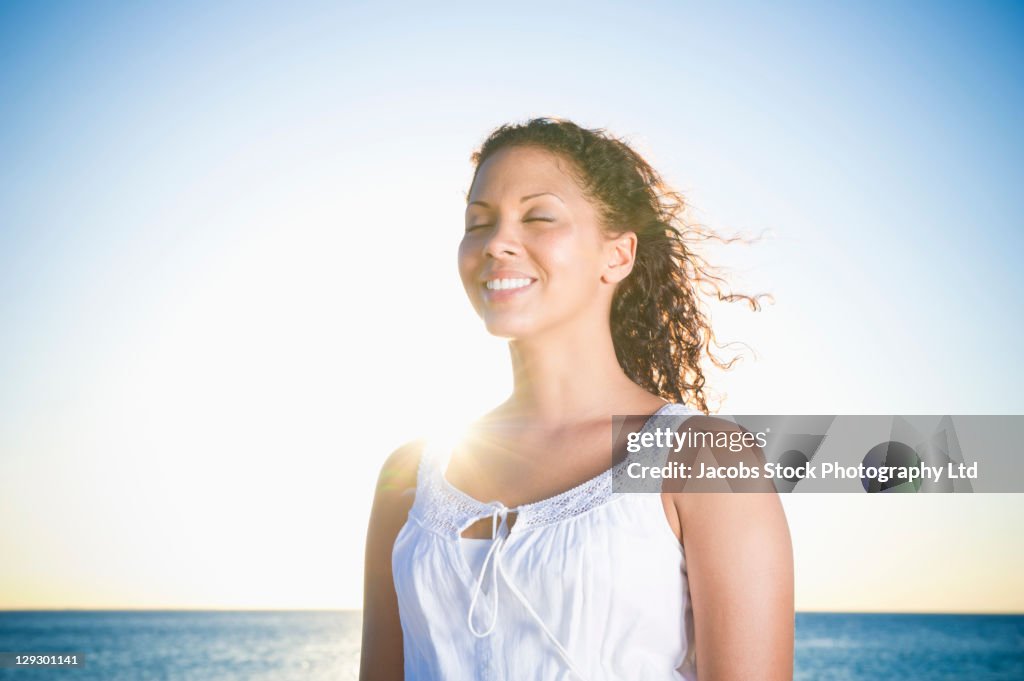 Mixed race woman standing near ocean