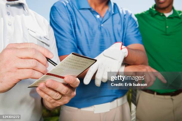 golfer standing with friends writing in golf score card - cartão de resultados imagens e fotografias de stock
