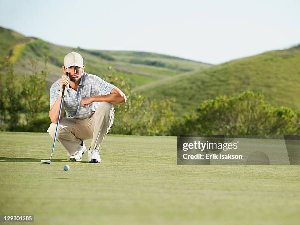 caucasian golfer checking the ground on golf course - golf putter stockfoto's en -beelden