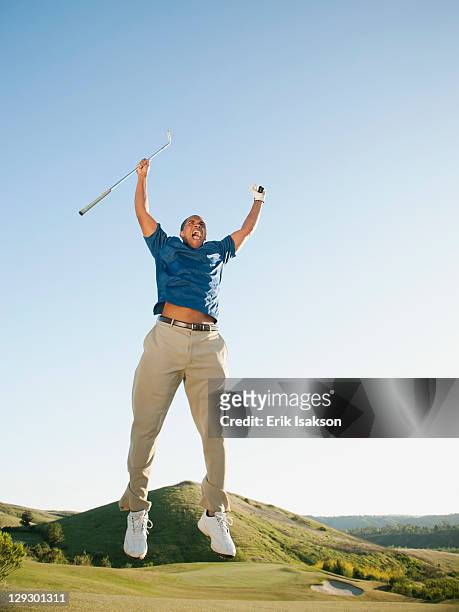 excited black golfer jumping in mid-air on golf course - golf excitement stock pictures, royalty-free photos & images