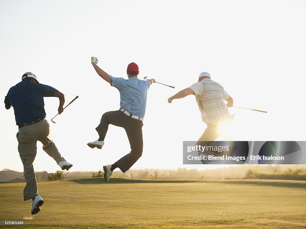 Excited golfers jumping in mid-air on golf course