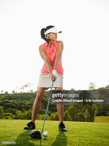 mixed race woman preparing to swing golf club on golf course - woman on swing foto e immagini stock