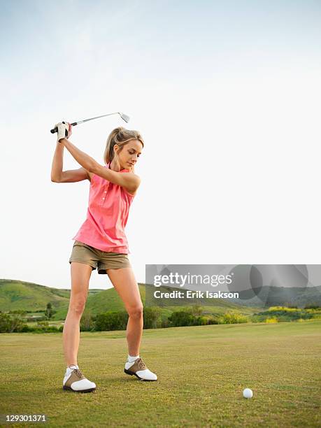 caucasian woman swinging golf club on golf course - golf club stock-fotos und bilder