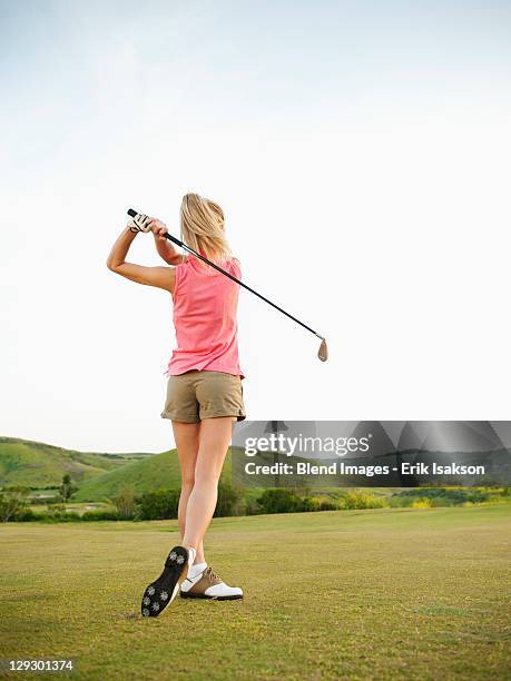 caucasian woman swinging golf club on golf course - golf swing stock-fotos und bilder