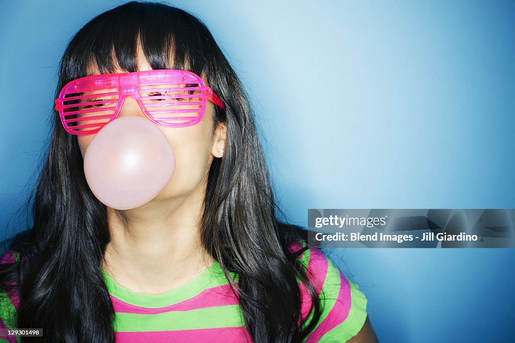 Mixed race woman blowing bubble with bubble gum