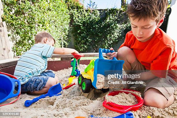 caucasian brothers playing in sandbox - zandbak stockfoto's en -beelden