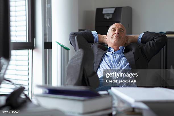 geschäftsmann entspannend mit füßen auf dem schreibtisch - casual businessman stock-fotos und bilder