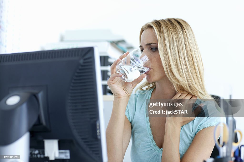 Businesswoman drinking water at desk