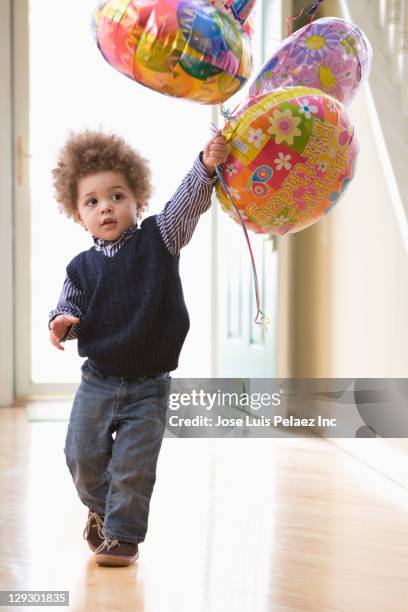 mixed race boy holding birthday balloons - globo de helio fotografías e imágenes de stock