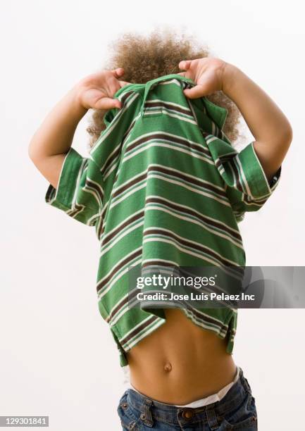 mixed race boy taking off shirt - entkleiden stock-fotos und bilder