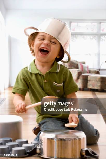 mixed race boy beating on kitchen pots - resourceful stock pictures, royalty-free photos & images