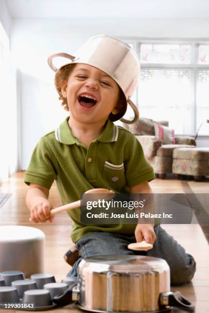 mixed race boy beating on kitchen pots - rådig bildbanksfoton och bilder
