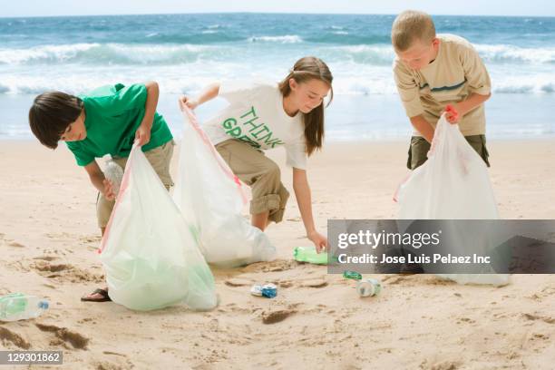 caucasian children picking up litter from beach - volunteer beach stock-fotos und bilder