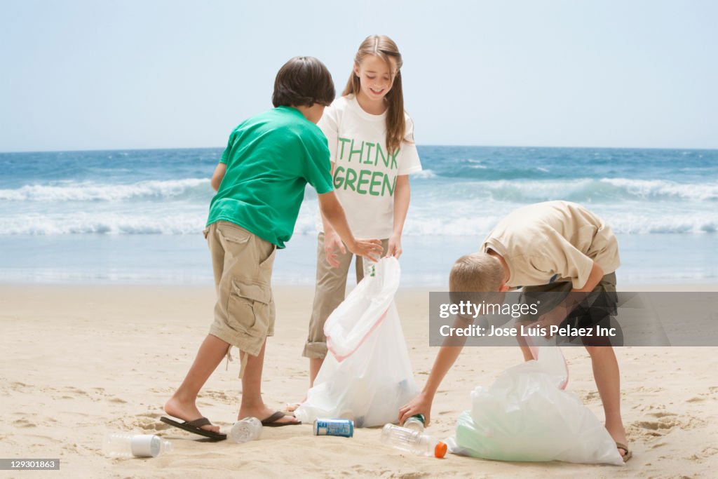 Caucasian children picking up litter from beach