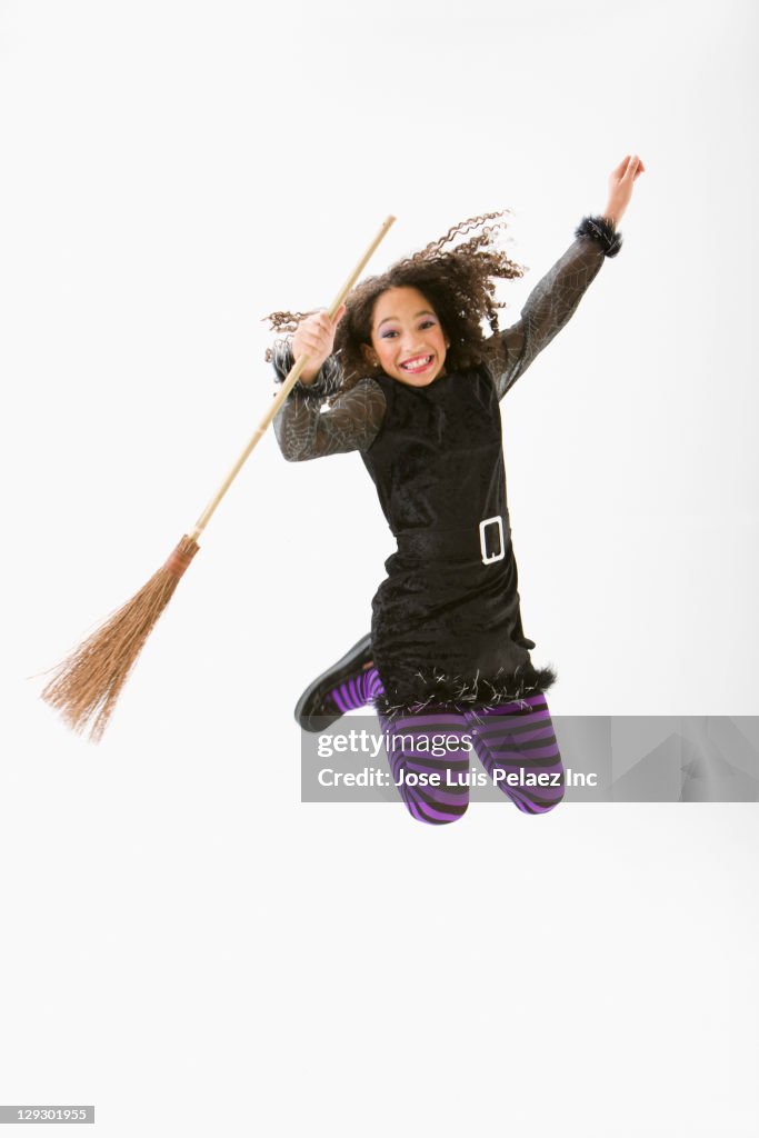 Mixed race girl in Halloween costume jumping and cheering