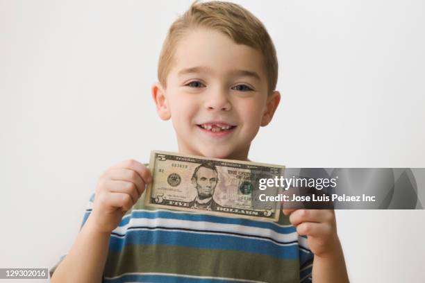 grinning caucasian boy holding five dollar bill - tooth fairy stockfoto's en -beelden