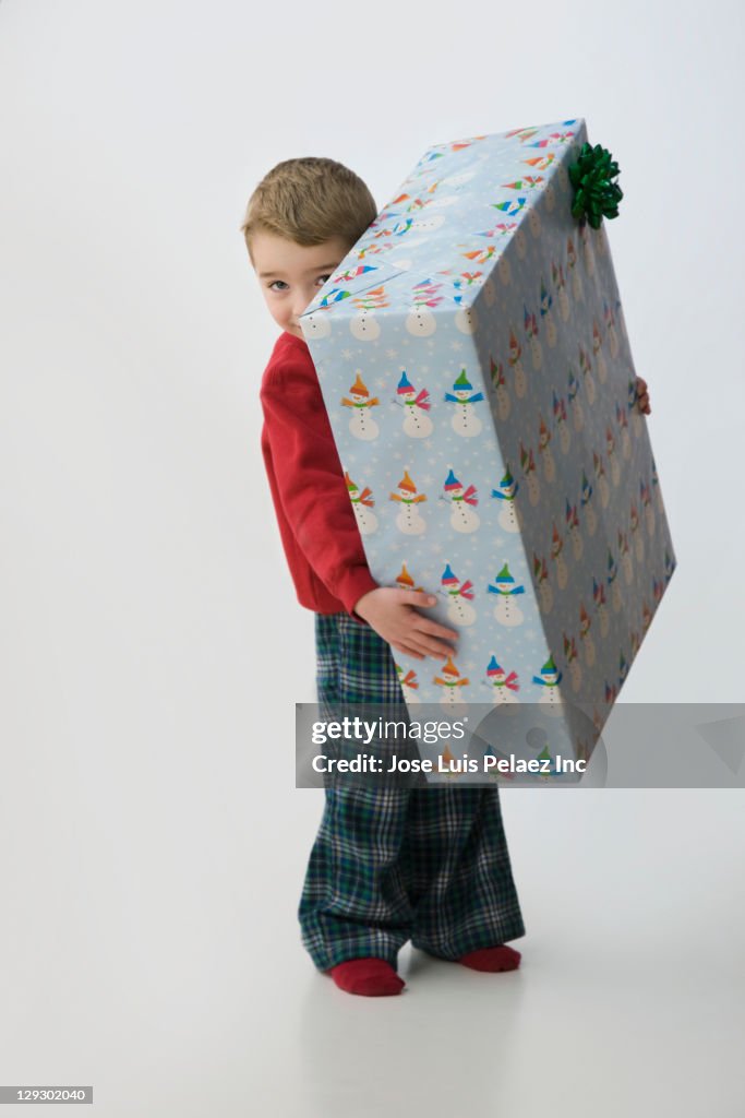 Caucasian boy holding large Christmas gift