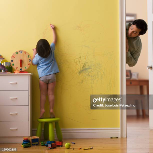 caucasian father watching son drawing on wall with crayon - unfug stock-fotos und bilder
