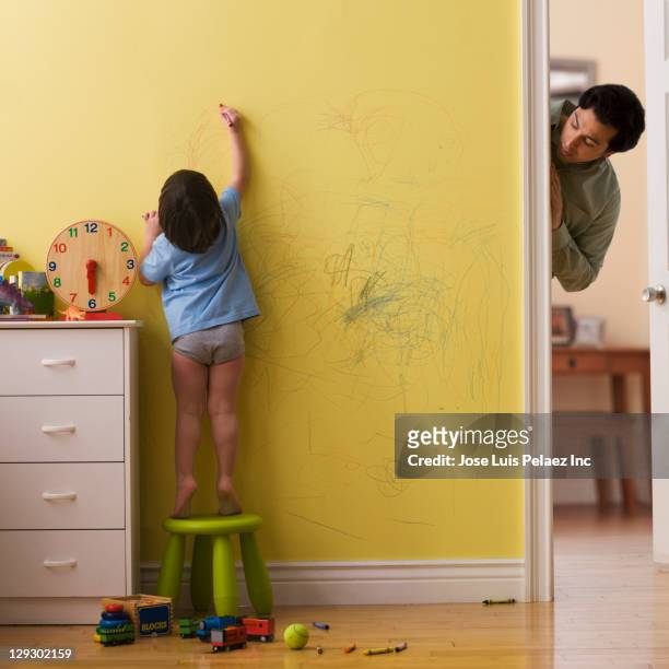 caucasian father watching son drawing on wall with crayon - misbehaving children stock pictures, royalty-free photos & images