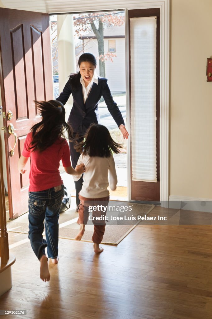 Asian girls greeting mother in doorway