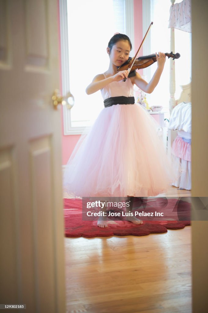 Asian girl in elegant dress playing violin