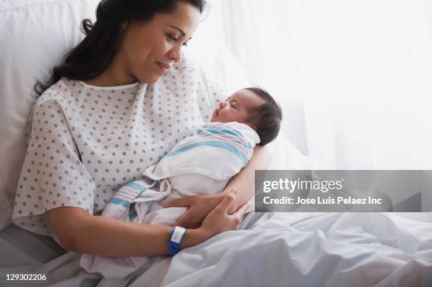 mother in hospital bed holding newborn baby girl - latin american and hispanic ethnicity newborn stock pictures, royalty-free photos & images