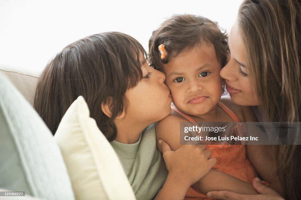 Brother and sister kissing baby sister