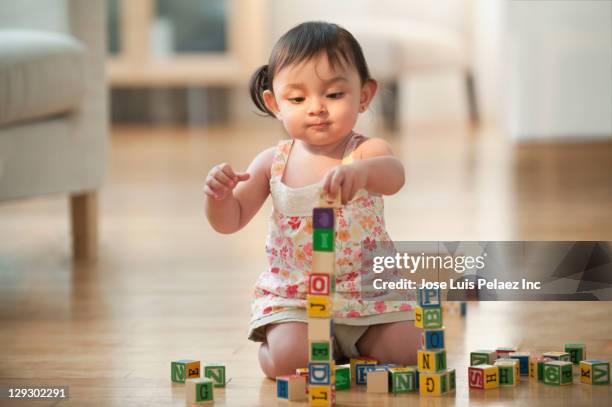 hispanic girl sitting on floor playing with alphabet blocks - ein weibliches baby allein stock-fotos und bilder
