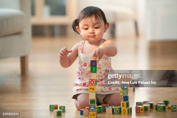 hispanic girl sitting on floor playing with alphabet blocks - baby text stock pictures, royalty-free photos & images