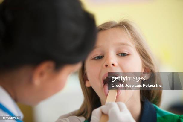 doctor using tongue depressor to looking in girl's mouth - sticking out tongue stock pictures, royalty-free photos & images