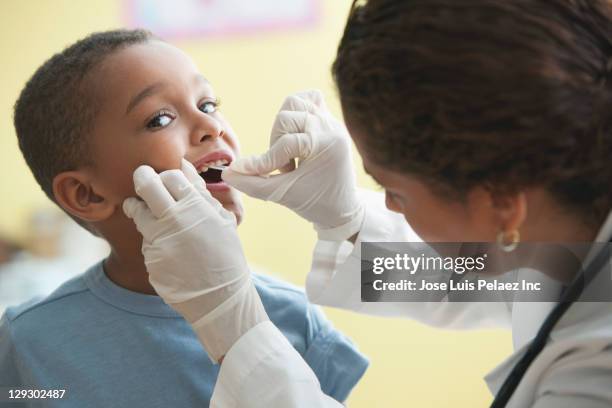 doctor looking into boy's mouth - dentista bambini foto e immagini stock
