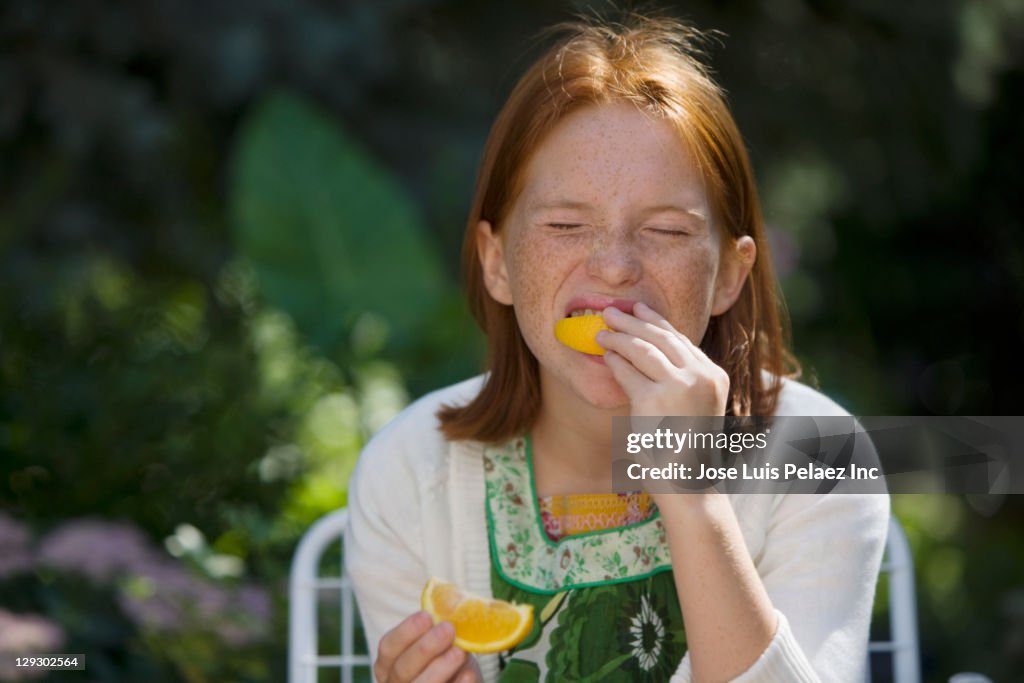 Caucasian girl eating slice of orange