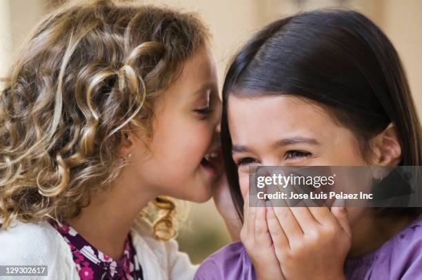 mixed race girls telling secrets - child whispering stockfoto's en -beelden