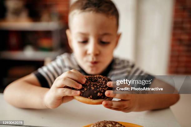 carino bambino biondo dolce, giocando e mangiando ciambelle - fat people eating donuts foto e immagini stock