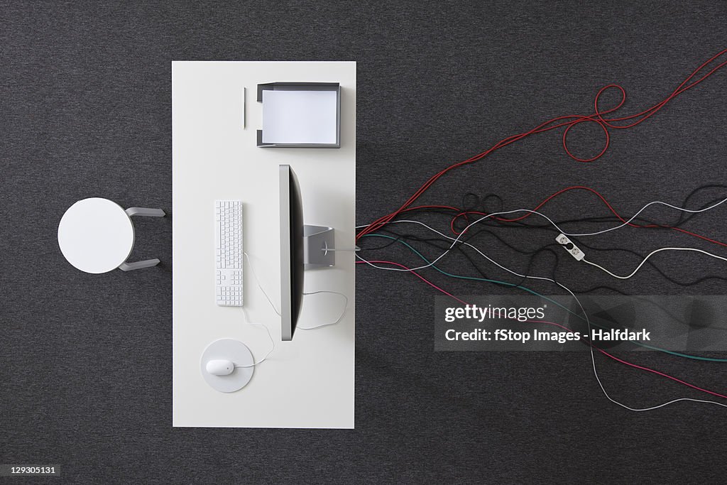 A desk in an office with multiple cables running under it, overhead view