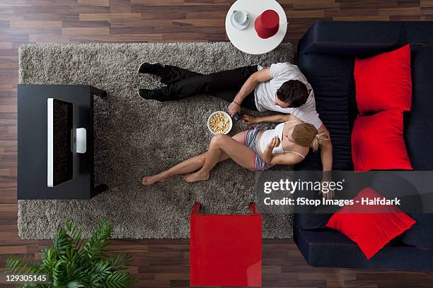 a couple eating popcorn and watching tv in their living room, overhead view - top of head stock pictures, royalty-free photos & images