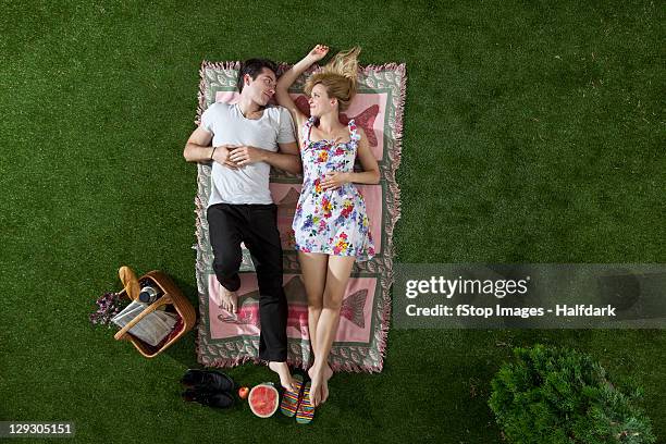 a couple lying on a blanket in a park looking at each other romantically, overhead view - romantic picnic stockfoto's en -beelden
