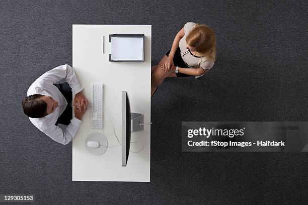 a businessman and businesswoman sitting across a desk from each other, overhead view - top of head stock pictures, royalty-free photos & images