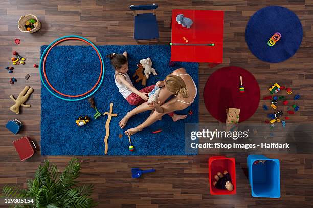 a mother and daughter playing with toys in a living room, overhead view - living room kids stockfoto's en -beelden